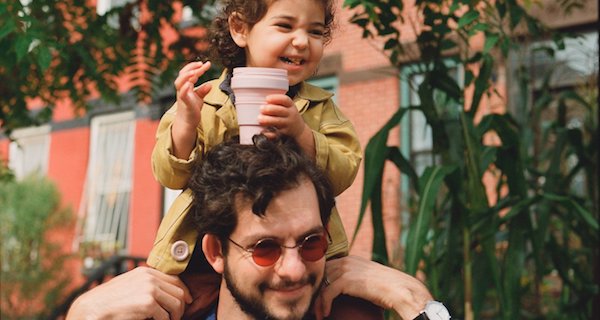 Father with child on his shoulders holding a Stojo cup